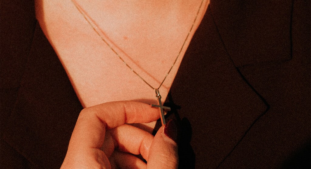 Wearing a cross necklace and holding in hand