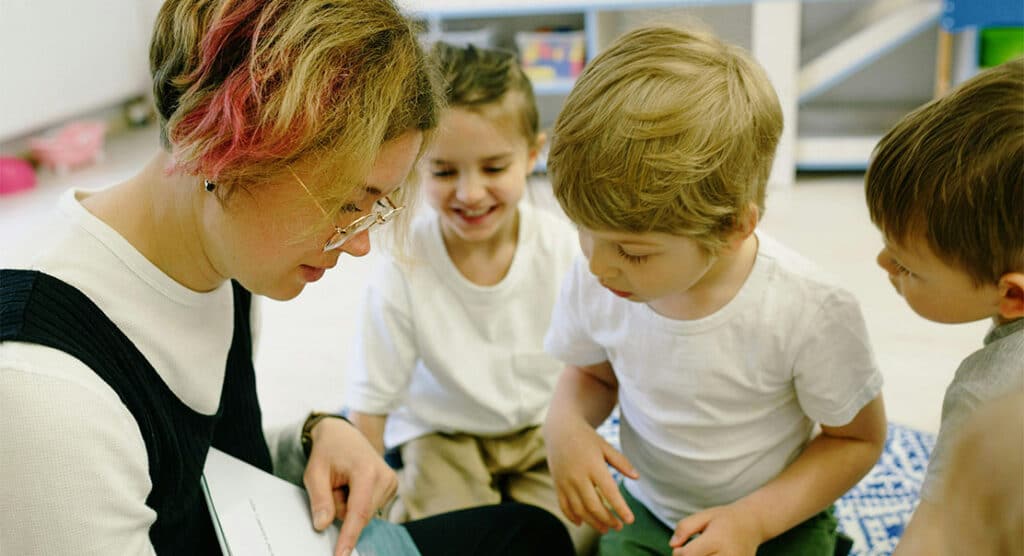 A woman teaching children to read a book